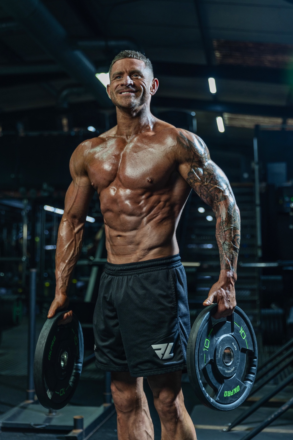 Garreg Jones smiling in the gym holding weight plates